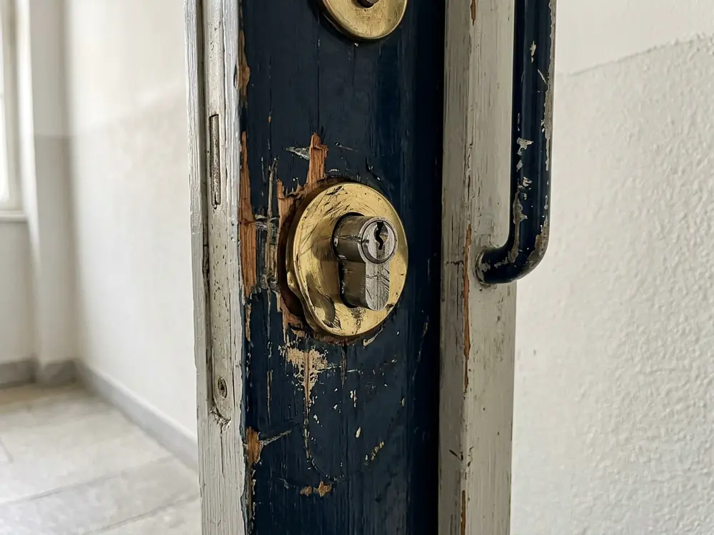 Zerkratzte Rosette und beschädigter Zylinder an einer Altbau-Wohnungstür nach einem Einbruchsversuch